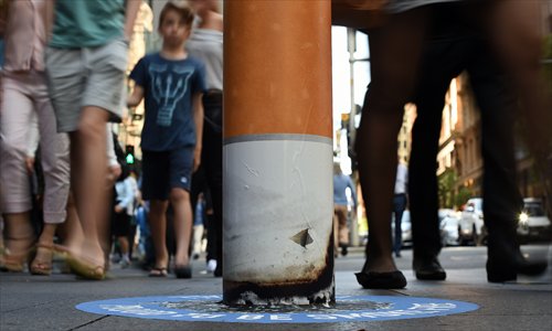 Shoppers walk past a bollard painted to represent a cigarette butt to raise awareness about new ‘no smoking’ zones in Sydney on Monday. Sydney’s famous shopping district, Pitt Street Mall, is now permanently smoke-free following a similar move at Martin Place in an effort to improve health and air quality in and around the city’s shopping malls. Photo: AFP
