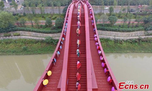 About 100 women show cheongsams on the knot-shaped pedestrian bridge in Changsha City, the capital of Central China’s Hunan Province, Oct. 23, 2016. The bright red unique design merges the idea of the Chinese knot and is inspired by the neighboring mountain ranges. The show was organized by the regional office of Chinese Cheongsam Association. (Photo: China News Service/Yang Huafeng)