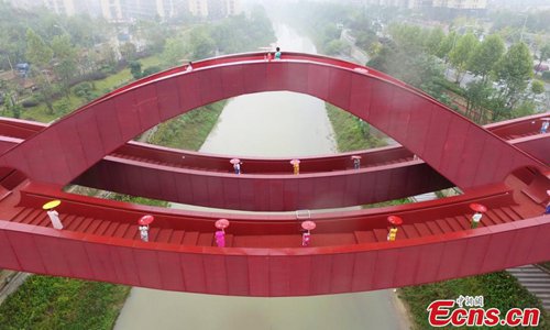 About 100 women show cheongsams on the knot-shaped pedestrian bridge in Changsha City, the capital of Central China’s Hunan Province, Oct. 23, 2016. The bright red unique design merges the idea of the Chinese knot and is inspired by the neighboring mountain ranges. The show was organized by the regional office of Chinese Cheongsam Association. (Photo: China News Service/Yang Huafeng)