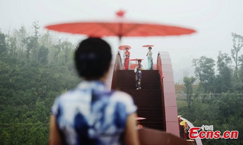 About 100 women show cheongsams on the knot-shaped pedestrian bridge in Changsha City, the capital of Central China’s Hunan Province, Oct. 23, 2016. The bright red unique design merges the idea of the Chinese knot and is inspired by the neighboring mountain ranges. The show was organized by the regional office of Chinese Cheongsam Association. (Photo: China News Service/Yang Huafeng)