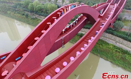 About 100 women show cheongsams on the knot-shaped pedestrian bridge in Changsha City, the capital of Central China’s Hunan Province, Oct. 23, 2016. The bright red unique design merges the idea of the Chinese knot and is inspired by the neighboring mountain ranges. The show was organized by the regional office of Chinese Cheongsam Association. (Photo: China News Service/Yang Huafeng)