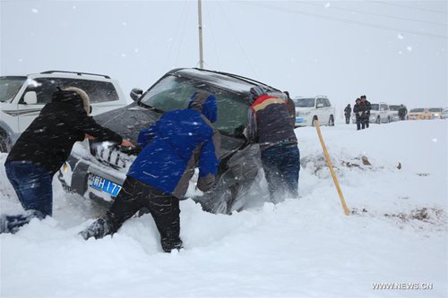 People try to move a vehicle in snow in Altay, northwest China's Xinjiang Uygur Autonomous Region, Nov. 16, 2016. The local authority launched a level-four emergency response after the city's snowstorm continued past 50 hours. (Xinhua/Ding Ning) 