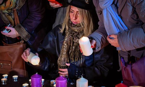 A woman lights up a candle to commemorate victims of the terrorist attack against Charlie Hebdo in 2015 during a commemoration at the Place of the Republic in Paris, France, on Jan. 7, 2016. Photo: Xinhua