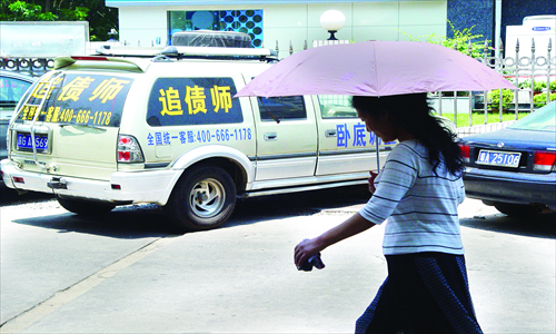 A woman passes by a vehicle with a debt collection ad and service telephone number on it. Photo: CFP