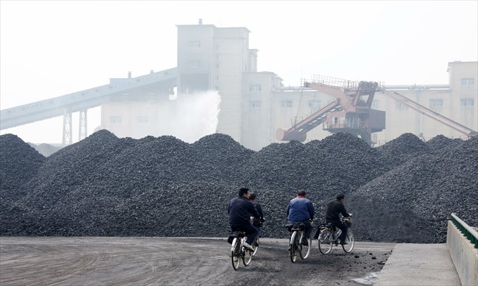 Piles of coke are laid down as workers pass by in a coal production plant in Huaibei, Anhui Province. Photo: CFP