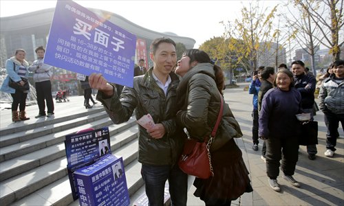 Qin Yu holds a banner inviting women aged 16 to 38 to kiss him in Wuhan, Central China's Hubei Province on Tuesday. He offered each woman 100 yuan ($16) per kiss and spent 1,000 yuan in just 10 minutes. Photo: CFP
