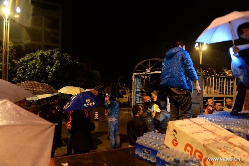 People get relief supplies in rain at a temporary settlement for quake-affected people in Lushan County, southwest China's Sichuan Province, April 23, 2013. A rainfall hit Lushan on Tuesday, the fourth day after a 7.0-magnitude jolted the county on April 20. (Xinhua/Li Gang) 