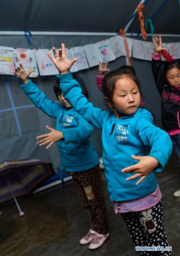 Children take a dance class in a temporarily-erected tent in Lushan County, southwest China's Sichuan Province, May 17, 2013. More than 100 children frequently participate in extra-curricular activities at this temporary school, which was opened on April 29 by volunteers and provides reading, painting and dancing classes to local children. The county was jolted by a 7.0-magnitude earthquake on April 20. (Xinhua/Liu Xiao) 