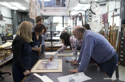 Nestor Barrio (R), manager of the Centro Tarea of the San Martin University, and dean of the Cultural Heritage Investigations Institute (IIPC, by its Spanish acronym) analyzes an artwork with members of the center, in the city of Buenos Aires, Argentina, on May 21, 2013. Within the spectra of tangible heritage objects, the Centro Tarea has specialized in the conservation and restoration of the picture and sculpture production, as well as in the conservation and restoration of bibliographic documentation and archive. (Xinhua/Martin Zabala)