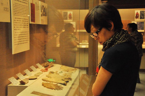 A woman looks at items on display in the museum of Dunhuang city, Northwest China's Gansu Province, August 30, 2012. Dunhuang, a major stop on the ancient Silk road well known for its Mogao Caves (Caves of 1,000 Buddhas), Crescent Lake and Mingsha Mountain, has witnessed a 40 percent increase in both tourists number and tourism industry's revenue in the first eight months in 2012 compared with the same period of last year. Photo: Xinhua