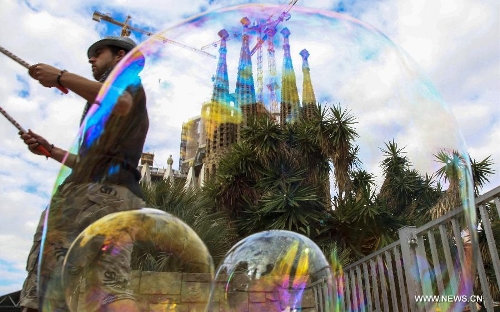 A busker makes soap bubbles in front of the Basilica and Expiatory Church of the Holy Family in Barcelona, Spain, on April 10, 2013. The Roman Catholic church, commonly known as the Sagrada Familia, was designed by Antoni Gaudi (1852-1926) and its construction had commenced in 1882. Although being incomplete after over 130 years, the church is a UNESCO World Heritage Site. (Xinhua/Sun Wen) 