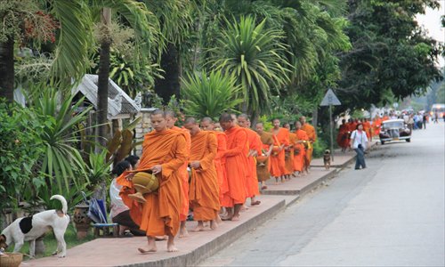 Giving alms to a line of monks as dawn breaks