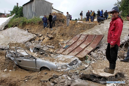 A local resident stands by a car stuck in mud in Beni Messous suburb, in upper Algiers, Algeria, on May 22, 2013. Heavy rain poured since Tuesday in several provinces in northern part of the country, claiming the life of one citizen, injuring three others, and causing extensive damages. (Xinhua/Mohamed Kadri) 