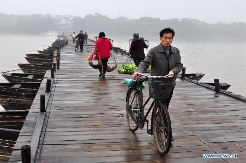 People walk on an ancient floating bridge across the Gongjiang River in Ganzhou, east China's Jiangxi Province, April 1, 2013. The wooden bridge, running 400 meters, is supported by some 100 floating boats anchored in a row. The bridge could date back to the time between 1163 and 1173 during the Song Dynasty, and has become a scene spot of the city. (Xinhua) 