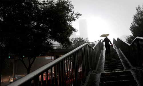 A pedestrian walks down an overbridge amid heavy rain in Beijing, capital of China, July 21, 2012. Photo: Xinhua