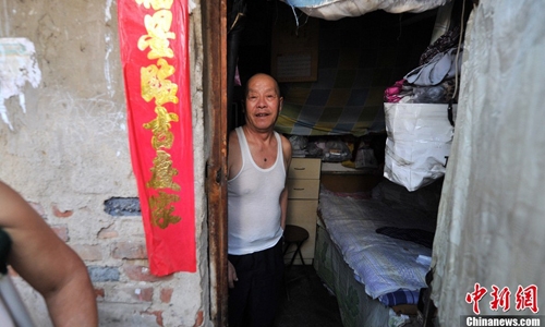 An elderly man looks out from his cluttered, dark room. Many seniors move to Huashiying in order to live with their children working in Beijing. Photo: Jin Shuo/chinanews.com 