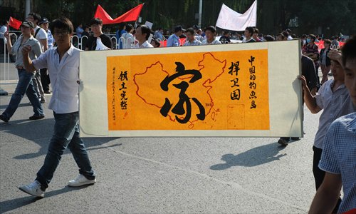 Two protestors hold a streamer, calling for people to defend the homeland and safeguard territorial sovereignty, in Beijing on Sunday. 
Photo: Zhang Siyang/GT
