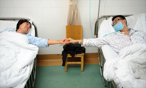Pan Daxiang (left), who donated part of her liver and a kidney to her son Chen Kai, holds Chen's hand on May 8 after successful transplant operations in Zhengzhou, Henan Province. Photo: CFP
