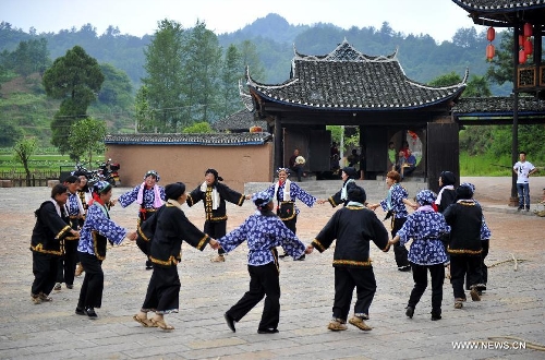 Villagers dance in front of a wooden Diaojiaolou, or stilted house in Shiyanping Village, Wangjiaping Township of Zhangjiajie City in central China's Hunan Province, June 16, 2013. The Shiyanping Village, located in the southeast of Wangjiaping, is one of the regions in Hunan where stilted houses are well preserved. With a toal of 182 existing stilted houses of the Tujia ethnic group, the village was listed as the seventh batch of important heritage sites under state protection in 2013. (Xinhua/Shao Ying)