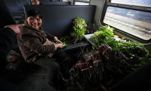 A woman sorts out her vegetables on the train. Photo: CFP