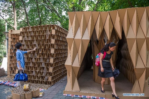 People visit paper houses in the Chongqing University, Chongqing, southwest China, May 21, 2013. Fourteen paper houses, made up with recycled paper by more than 200 freshman, were displayed in the Faculty of Architecture and Urban Planning of the university on Tuesday. (Xinhua/Chen Cheng) 