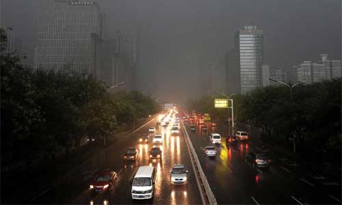 Vehicles turn on head lights while running amid heavy rain in Beijing, capital of China, July 21, 2012. Photo: Xinhua