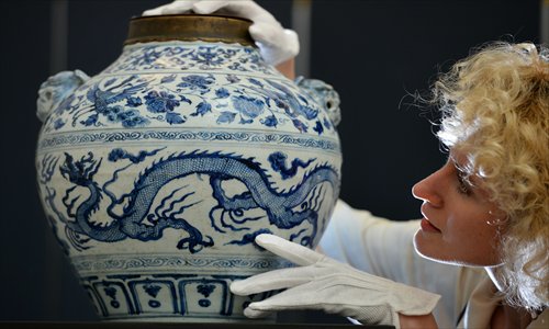 An employee Friday poses with a Yuan Dynasty (1279-1368) blue and white 