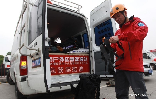 A member of the Ramunion Rescue, a rescue team from Hangzhou, capital of east China's Zhejiang Province, arranges his outfit at the Xinjin Service Area on the Chengdu-Ya'an Highway after 22-hour drive in Ya'an, southwest China's Sichuan Province, April 21, 2013. Six members of the Hangzhou Outdoors Emergency Rescue Team arrived in the earthquake-hit Ya'an City after driving for consecutive 22 hours on Sunday. (Xinhua/Pei Xin)  
