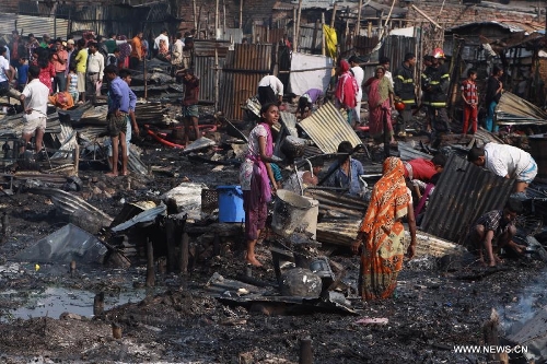 People gather around the site of a fire accident in a slum in Dhaka, Bangladesh, Feb. 3, 2013. About 100 shanties were destroyed in the accident, official said. (Xinhua/Shariful Islam) 
