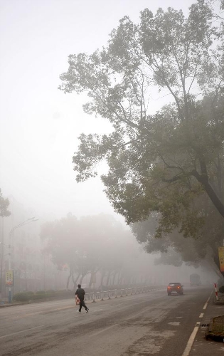 A citizen crosses the fog-shrouded Chongxin Road in Guilin, southwest China's Guangxi Zhuang Autonomous Region, Jan. 13, 2013. Dense fog on Sunday hit China's east and central regions from the northeast to the south, causing serious air pollution. (Xinhua/Lu Bo'an) 