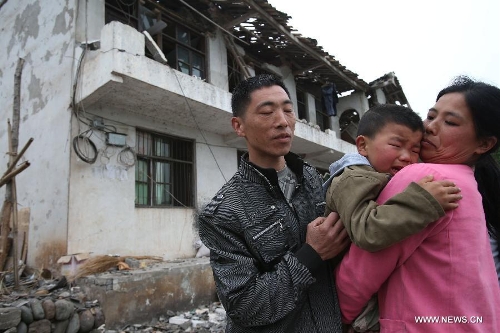 The family of Song Shiyong (L) stand in front of their damaged house at Wangjia Village of Longmen Township in Lushan County, southwest China's Sichuan Province, April 21, 2013. A 7.0-magnitude earthquake hitting Lushan County Saturday morning has left 179 people dead till 9:25 Beijing Time (0125 GMT) on April 21, the China Earthquake Administration has announced. (Xinhua/Jin Liwang)  