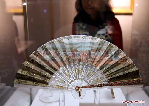 A visitor looks at a folding fan presented on the exhibition of 