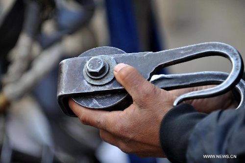 A resident of Shuangmidi Village holds a metal pulley used on a zip-line before crossing the Nujiang River in Liuku County of Nujiang Lisu Autonomous Prefecture, southwest China's Yunnan Province, Feb. 2, 2013. More than 98 percent of Nujiang Lisu Autonomous Prefecture is occupied by mountains and valleys. The zip-lines have been quite popular transportation method along the Nujiang River since the ancient time. However, as transport conditions improve in recent years, a growing number of traditional zip-lines along the Nujiang River Valley have been dismantled or replaced by bridges. (Xinhua/Lin Yiguang)  