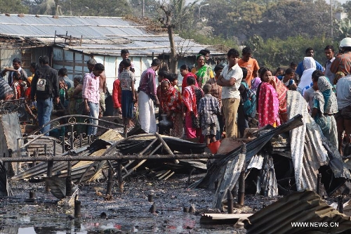 People gather around the site of a fire accident in a slum in Dhaka, Bangladesh, Feb. 3, 2013. About 100 shanties were destroyed in the accident, official said. (Xinhua/Shariful Islam)