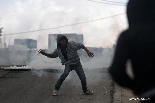 A Palestinian protester throws a tear gas canister back at Israeli soldiers during clashes in the West Bank village of al-Khader near city of Bethlehem, April 5, 2013. (Xinhua/Luay Sababa) 