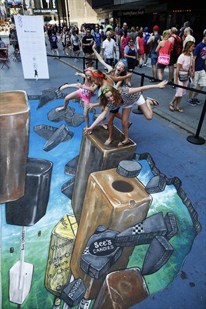 Children pose for a photo atop a 3D street art piece depicting giant lollypops at Times Square in New York on Wednesday to celebrate the upcoming National Lollypop Day on July 20. Photo: IC