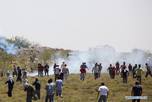 Palestinian protesters take cover of gas fired by Israeli soldiers during clashes after a protest against settlement's expansion and settlers attack in the west bank village of Dir Jrer near Ramallah on April 26, 2013. Six protesters were injured during clashes between Palestinians and Israeli soldiers. (Xinhua/Fadi Arouri) 