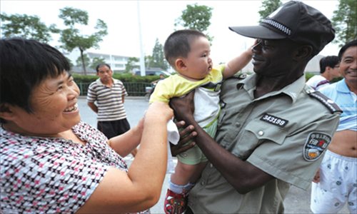A foreign Chengguan holds a Chinese baby as his appreciative guardian watches.
