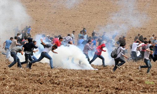 Protesters flee as tear gas explodes in a field during a demonstration near Dicle University, in Diyarbakir, Turkey on Tuesday. Leftist Kurdish students protested after clashes between left and right-wing groups inside Dicle University. Photo: AFP