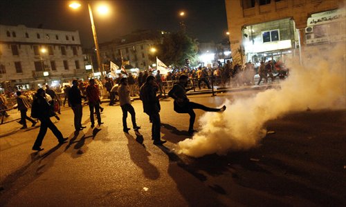 Demonstrators kick away a tear gas canister as they remove a barrier from outside the Egyptian Presidential Palace’s main gate during a demonstration on Tuesday in Cairo.  Photo: AFP