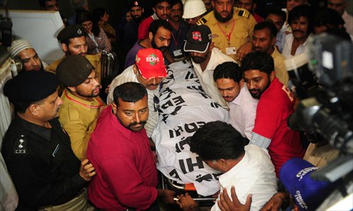 Pakistani rescuers carry the dead body of Zohra Hussain, vice president of the women's wing of Pakistan Tehreek-e-Insaf (PTI) in the province of Sindh, in Karachi on Saturday. Photo: <em>AFP</em>