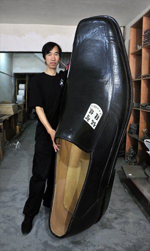 Chen Mingzhi, a shoe designer from Wenling, Zhejiang Province, poses with his 1.9-meter-long shoe. Chen spent two months making it, hoping to break a world record. Photo: CFP