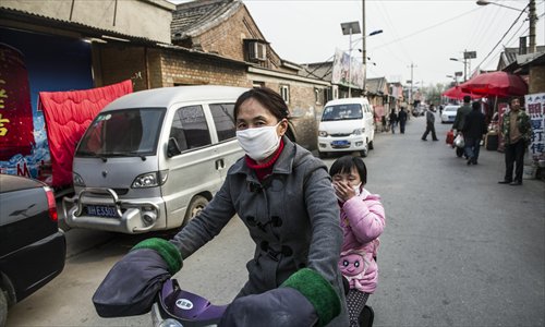 A mother and her child, with their masks on, pass by the home of a four-year-old H7N9 flu virus carrier surnamed Zhu in Naidong village, Chaoyang district, Beijing, on Monday. Photo: Li Hao/GT