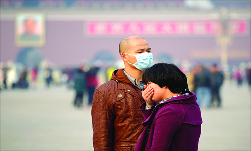A man wears a face mask as another visitor covers her mouth at Tiananmen Square in Beijing on November 5. Photo: CFP