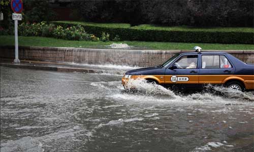 A taxi drives in heavy rain in Beijing, capital of China, July 21, 2012. Photo: Xinhua