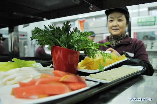  A working staff sides dishes in a half portion compared to the normal at a hot pot restaurant in Lanzhou, capital of northwest China's Gansu Province, Jan. 30, 2013. A 