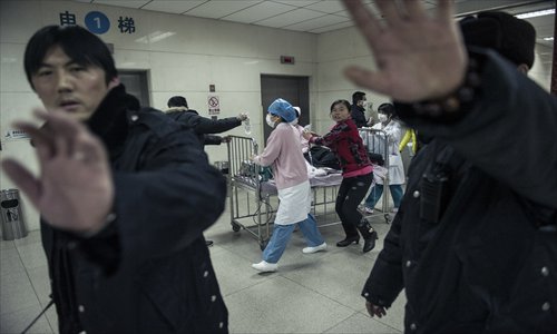 Security guards obscure photos being taken of a brain-dead toddler as she is transferred to a different ward at Tongren Hospital on January 10. Her father is accused of beating her. Photo: Li Hao/GT
