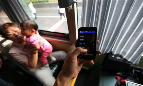 A passenger searches for a Wi-Fi signal on the No.82 bus in the Lujiazui area of Pudong New Area Wednesday. A total of 150 buses on seven routes will be outfitted with free wireless Internet access for riders. Photo: Cai Xianmin/GT
