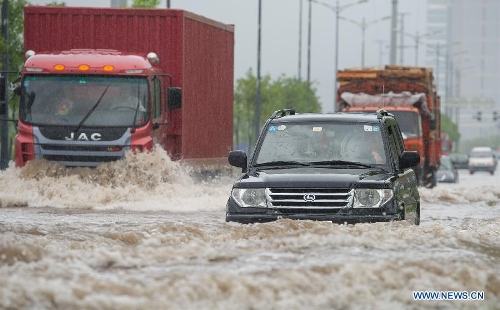  Vehicles run through a waterlogged road in southwest China's Chongqing Municipality, June 9, 2013. Heavy rainfall hit Chongqing as the city issued a red rainstorm warning here on Sunday. (Xinhua/Chen Cheng) 