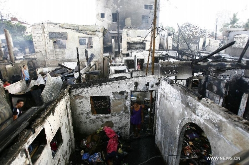 Residents retrieve reusable materials from their burnt homes after a fire razed a residential area in Quezon City, the Philippines, May 21, 2013. More than 200 families were left homeless in the fire. (Xinhua/Rouelle Umali)